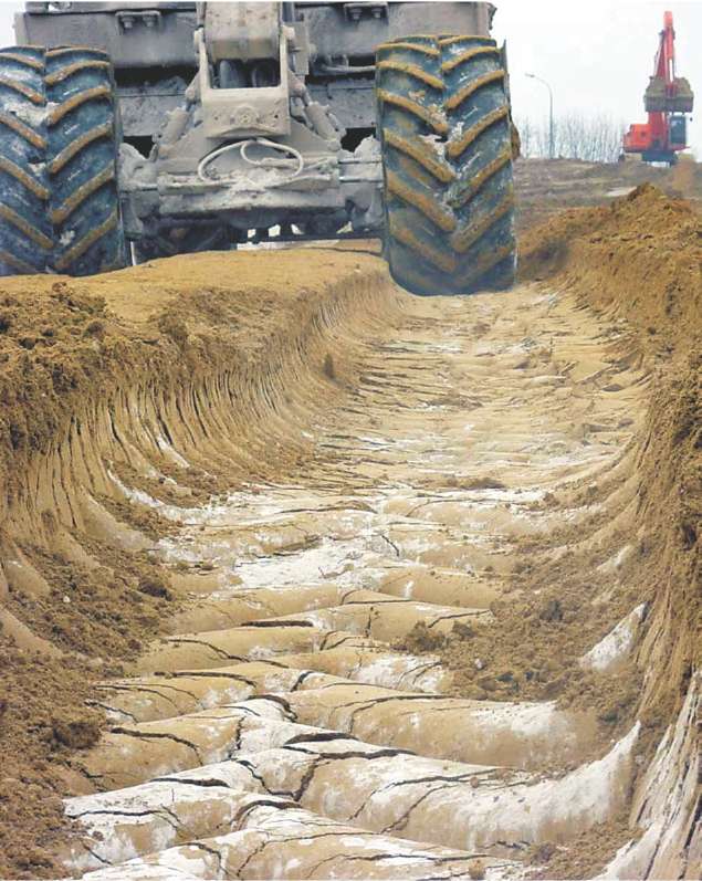 A photograph of a large vehicle on a building site. Lime has been spread over the ground and has made the soil firmer.